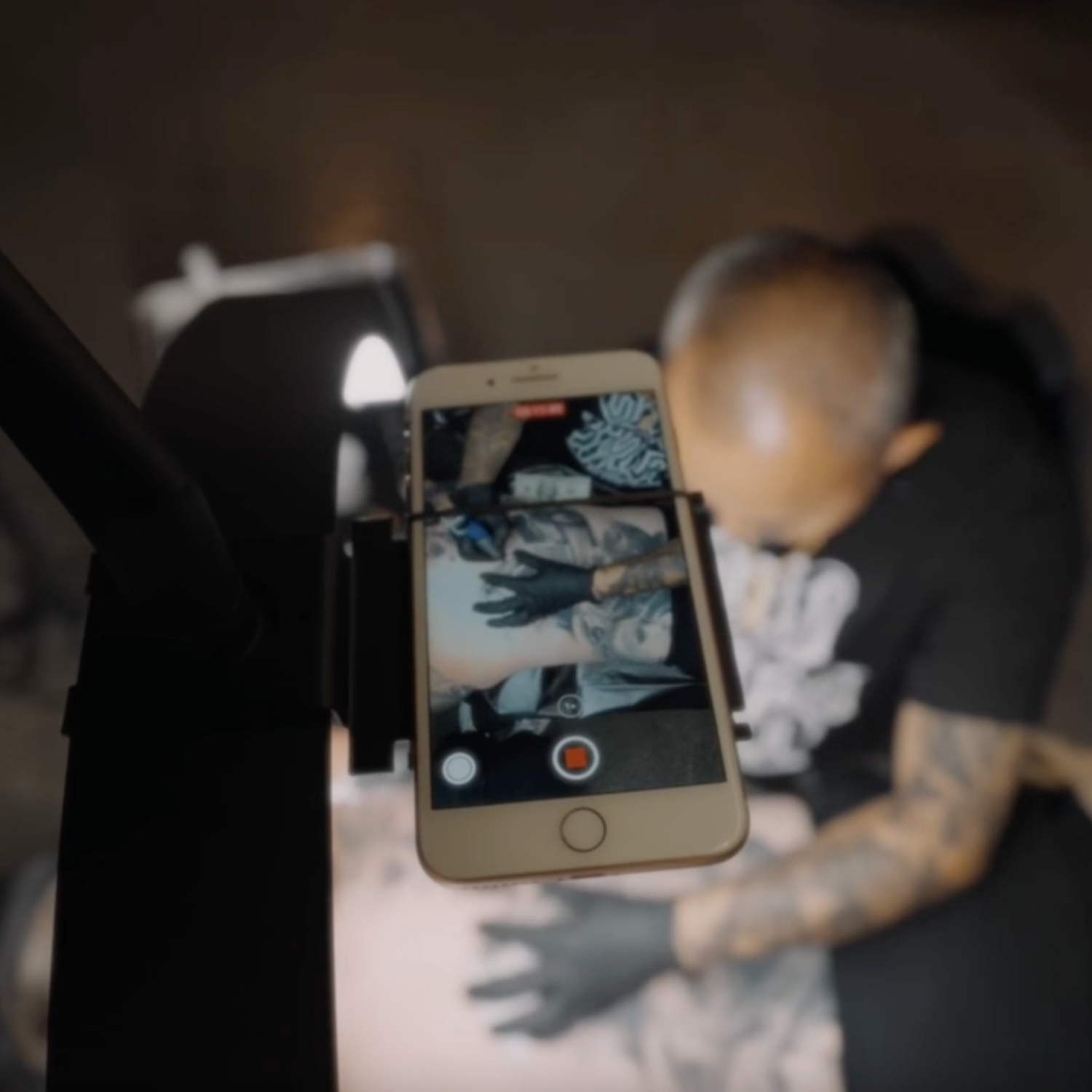 Person holding a phone with a tattoo design on screen, blurred background