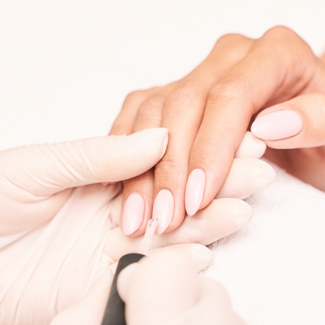 Gloved manicurist applying polish during a manicure