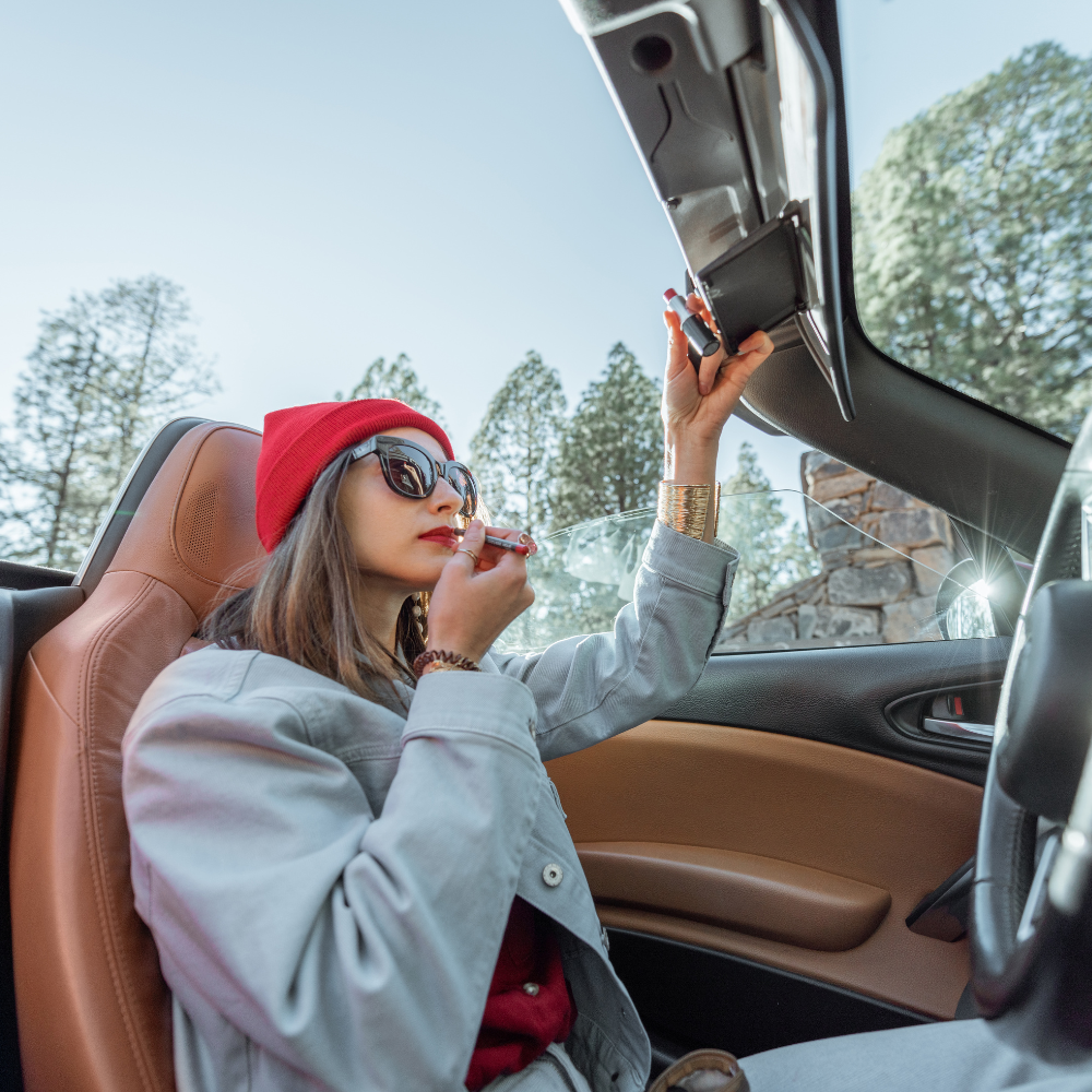 Woman using CosmoGlo visor mirror for makeup in car