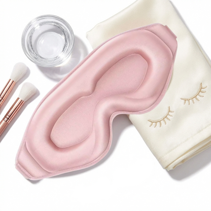 Pink eye mask with white pillow, makeup brushes, and false eyelashes on a white background