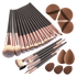 A 20-piece makeup brush set with black handles, rose gold ferrules, and dual-toned bristles, shown alongside four brown makeup sponges on a white background.