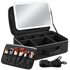 Black makeup case with an integrated LED light mirror, shown open with interior compartments, a brush holder with makeup brushes, and a detachable shoulder strap on a white background.