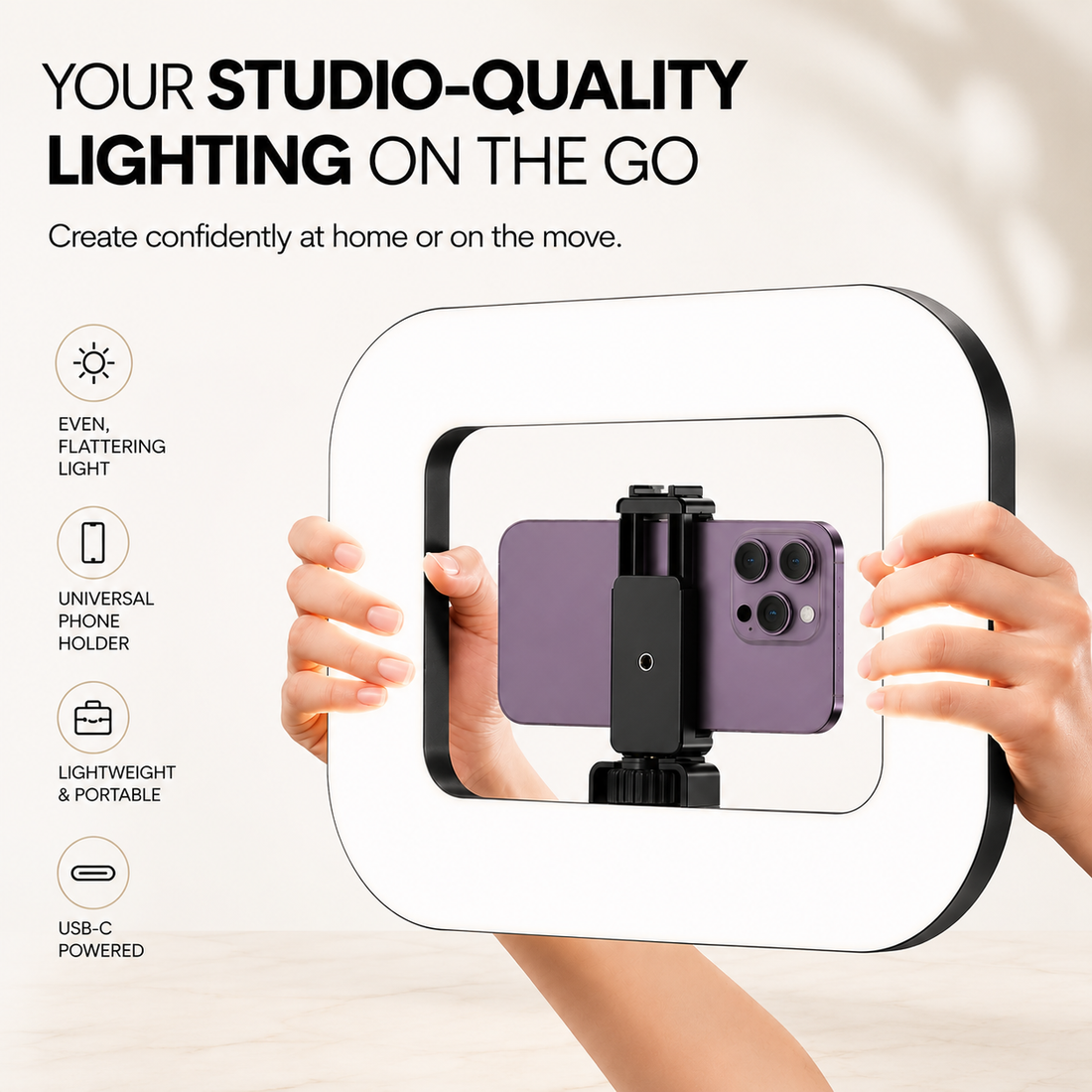 A portable square ring light with a built-in phone holder, shown being held by two hands. The ring has a white face and black frame, with a purple smartphone mounted inside.