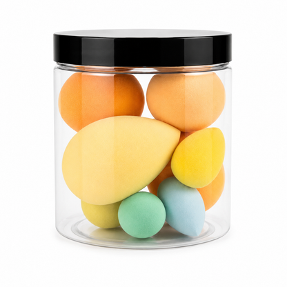 A clear cylindrical jar with a black lid containing multiple makeup blending sponges in pastel and warm tones including yellow, orange, mint green, light blue, and pale yellow, shown on a white background.