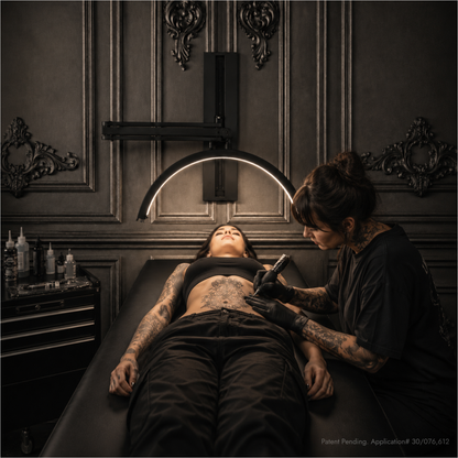 A tattoo artist wearing black gloves and a black shirt works on a client&