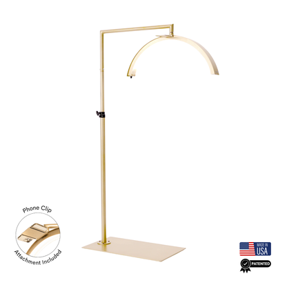 Gold floor lamp with phone clip attachment on a white background