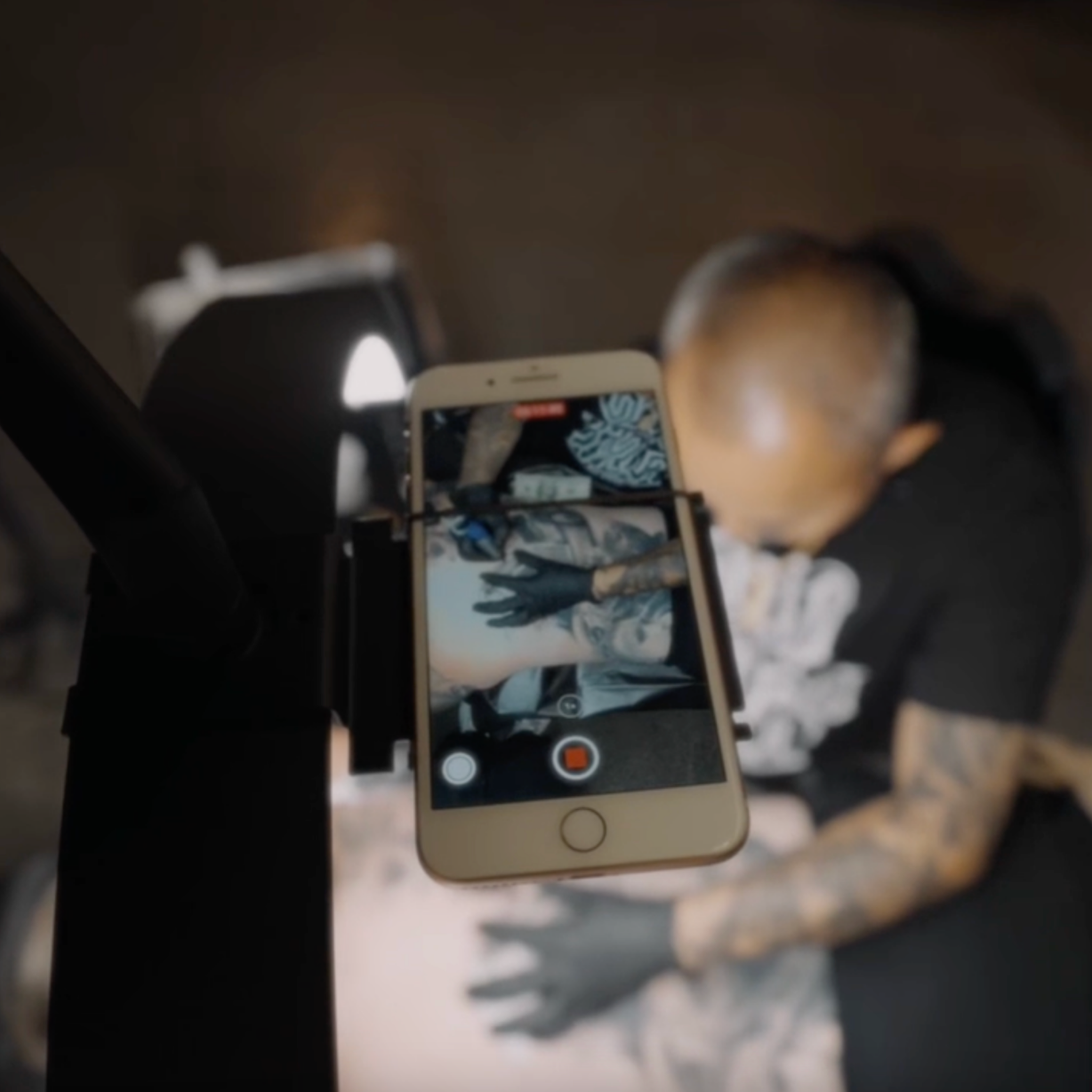 Person holding a phone with a tattoo design on screen, blurred background